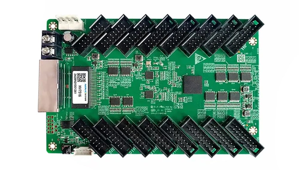Green development board with two rows of black edge connectors along the top and bottom, plus a metal module on the left for hardware prototyping.